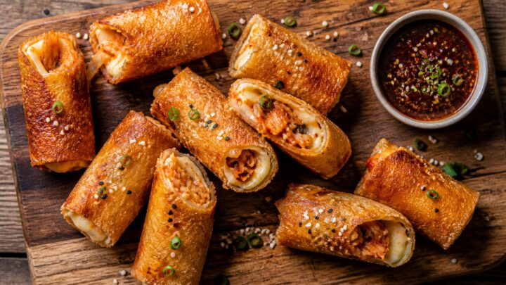Crispy air fryer kimchi grilled cheese roll ups arranged on a plate with dipping sauce