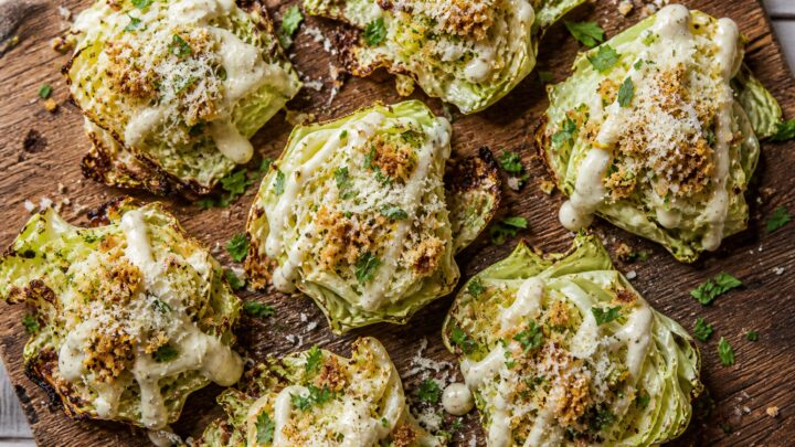 Crispy smashed cabbage Caesar bites on a serving platter drizzled with dressing, Parmesan, and breadcrumbs.
