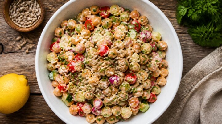 Lemon tahini crunch chickpea salad in a white bowl with cucumbers and bell peppers