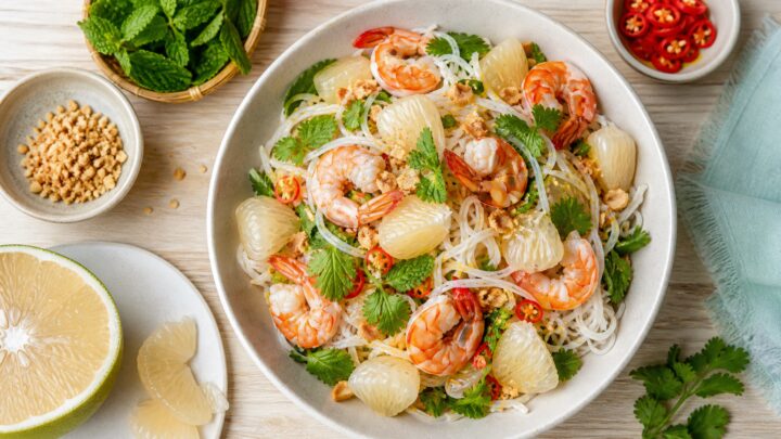 A bowl of pomelo shrimp rice noodle salad with fresh herbs and crushed peanuts on top