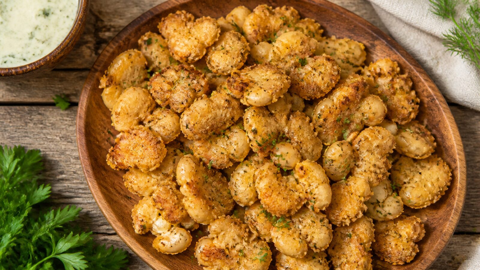Golden crispy air fryer ranch smashed white beans piled on a wooden board, perfectly browned and seasoned.