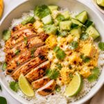 Spicy Mango Cottage Cheese Chicken Bowls in a bowl with rice, mango cottage cheese mixture, sliced chicken, cucumber, and cilantro.