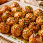 Juicy air fryer chicken meatballs glazed with peach bourbon sauce, garnished with parsley and sesame seeds.