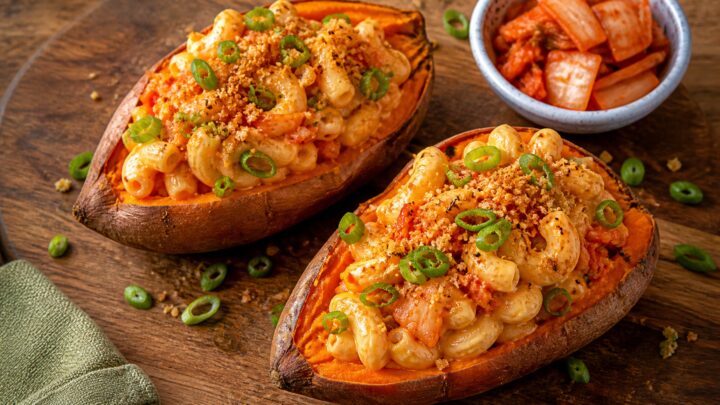 Kimchi mac and cheese stuffed sweet potatoes on a baking sheet, golden and topped with green onions