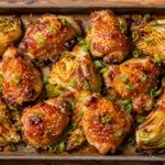Spicy apricot chicken traybake with cabbage on a sheet pan, garnished with green onions and sesame seeds
