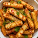 Air fryer sweet chili halloumi fries in a white bowl, golden and crispy, garnished with cilantro.
