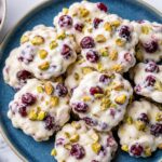 Cherry pistachio frozen yogurt clusters on a baking sheet with parchment paper, ready to freeze
