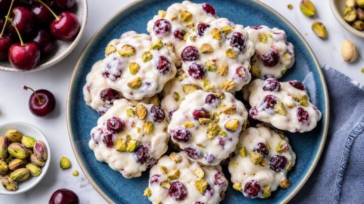 Cherry pistachio frozen yogurt clusters on a baking sheet with parchment paper, ready to freeze