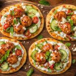 Harissa honey chicken meatball flatbreads topped with tzatziki, cucumber, and cherry tomatoes on a wooden board.