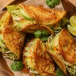 Crispy hot honey cabbage pancake wraps on a plate with avocado and lime wedges