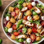 Crispy rice chicken parm salad with greens, cherry tomatoes, fresh mozzarella, and balsamic dressing in a bowl