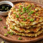 Crispy cabbage chow mein pancakes golden brown on a plate with soy sauce and green onions