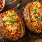 Air Fryer Kimchi Corn Cheese Stuffed Potatoes with melted cheese and green onions on a plate