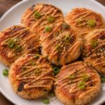 Crispy air fryer sesame ginger salmon rice cakes on a plate with sesame seeds and sriracha mayo drizzle