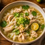 A hearty bowl of calamansi garlic chicken rice soup garnished with fresh cilantro and green onions