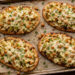 Cabbage Caesar Chickpea Flatbread Melts on a baking sheet, topped with melted cheese and fresh parsley