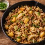 Swicy pineapple cabbage turkey skillet in a cast iron pan with green onions and sesame seeds garnish