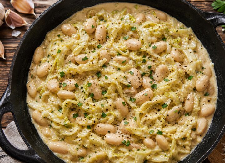 Roasted garlic cabbage alfredo beans in a cast iron skillet topped with fresh parsley