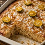 Calamansi Coconut Oat Pancake Bake in a baking dish with toasted coconut sprinkle and a drizzle of syrup