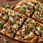 Roasted pear blue cheese chicken flatbread on a baking sheet, sliced and drizzled with balsamic honey, with arugula garnish
