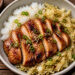 Air Fryer Chicken Adobo Cabbage Rice Bowls with glaze, green onions, and sesame seeds in a bowl on a wooden table