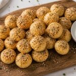 Crispy air fryer cottage cheese bagel bites with everything bagel seasoning on a wooden board, served with ranch dipping sauce.