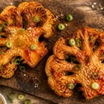 Crispy air fryer sriracha maple cauliflower steaks on a white plate, garnished with green onions and sesame seeds