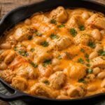 Buffalo Ranch Butter Bean Chicken Skillet in a cast iron pan, topped with melted cheddar and fresh parsley, served with rice on the side.