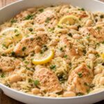 Chicken piccata butter bean orzo in a white skillet, garnished with fresh parsley.