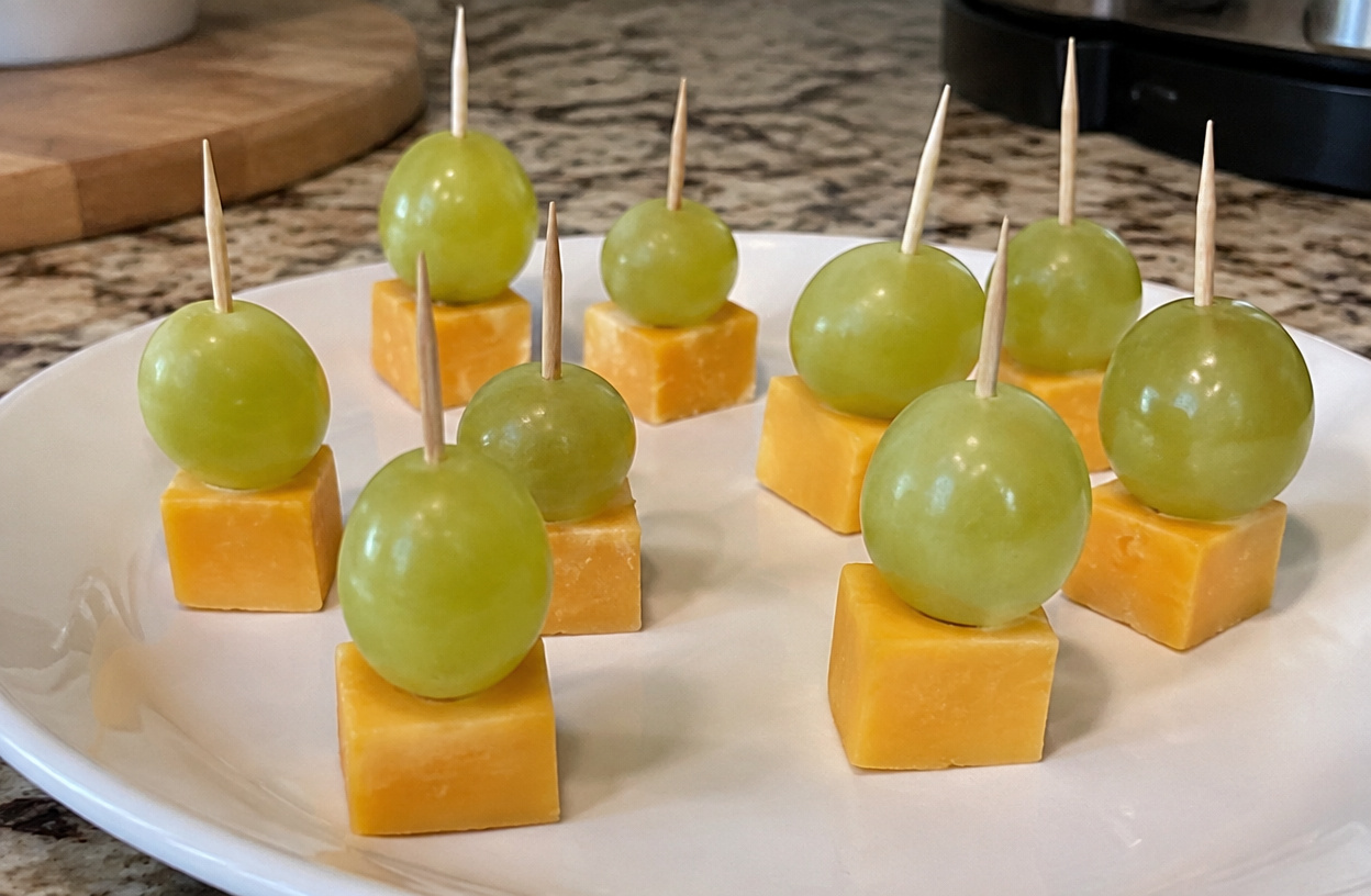 Cheddar cheese and green grape bites on toothpicks.