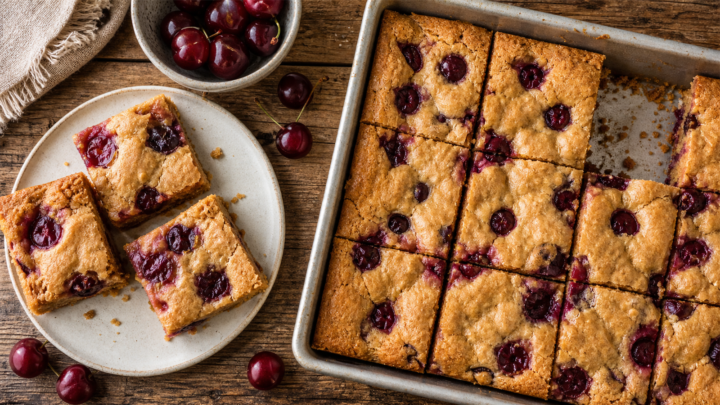 Sour cherry brown butter blondies cut into squares on a white plate, showing gooey cherries and golden edges.