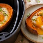 Air fryer gochugaru sweet potato egg boats topped with green onions and sesame seeds on a plate